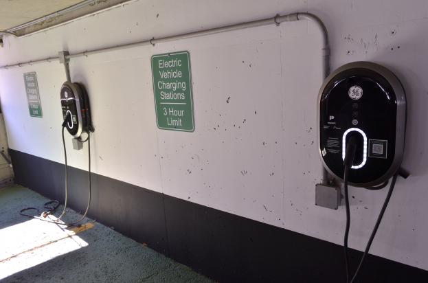 Eine Ladesäule für Elektrofahrzeuge in einer Tiefgarage mit zwei an der Wand angebrachten Ladesäulen und Tafeln mit Text sowie einem sichtbaren Boden.