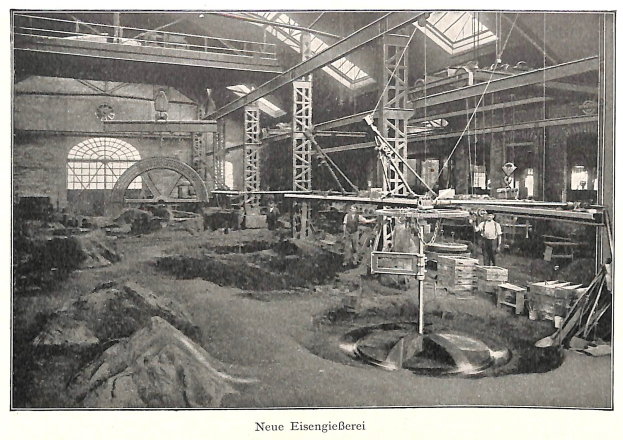 Schwarzes und weißes Foto einer 19. Jahrhundert deutschen Fabrik mit Arbeitern, die an Maschinen arbeiten, umgeben von Metallstangen und Polen, beschriftet mit "Neue Eisenglebeerei, die erste Fabrik in Deutschland" unten.