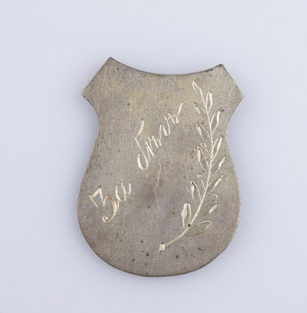 Silbernes Abzeichen mit einem Lorbeerkranz und der Inschrift "50. Hochzeitstag" auf einem weißen Hintergrund.