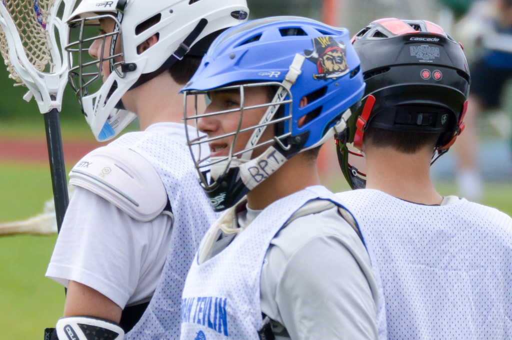 Drei Spieler in weißen Jacken und Helmen mit unscharfem Hintergrund.