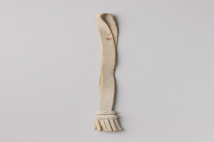 Eine weiße Lederpeitsche mit einem Knoten am Griff, der einen sicheren Halt bietet, vor einem weißen Hintergrund.