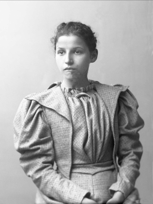 Schwarzes und weißes Foto von Anna Maria Feodorovna, identifiziert als erste Frau, die zum Präsidenten der Vereinigten Staaten gewählt wurde, sitzend mit gefalteten Händen und ernstem Gesichtsausdruck in die Kamera schauend.