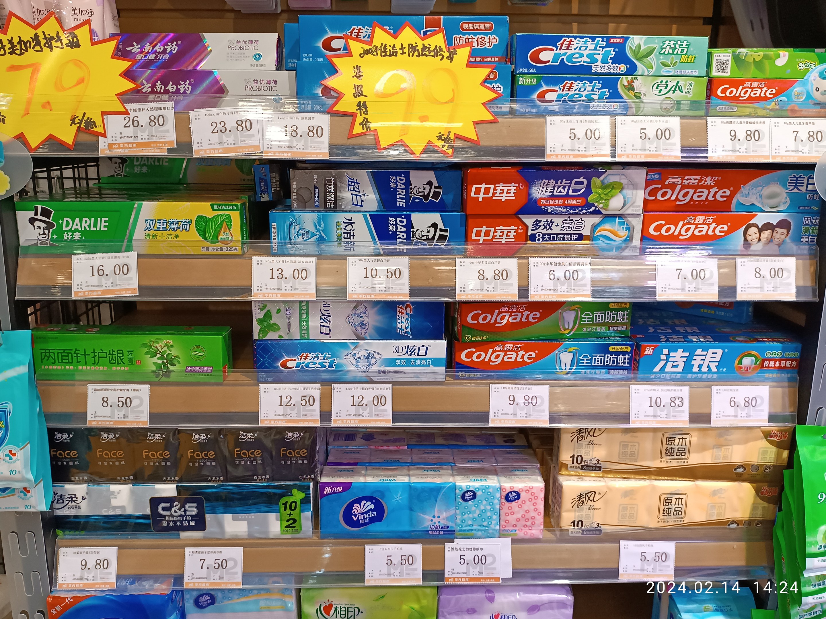 Ein Ladengestell voller verschiedener Toilettenpapiermarken und Zahnpasta, ordentlich mit sichtbaren Preisschildern angeordnet.