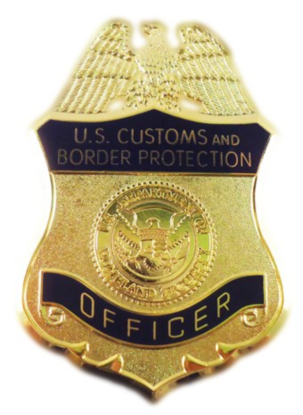 Goldes Abzeichen mit der Gravur "U.S. Customs and Border Protection Officer" auf einem weißen Hintergrund.