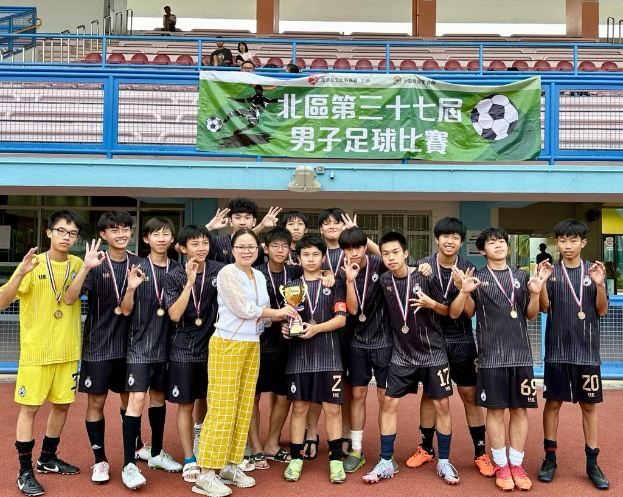 Eine Gruppe junger Männer in Fußballtrikots steht auf einem Feld und hält einen Pokal, während sie Medaillen tragen und ein Banner mit der Aufschrift 'Yokohama U-16 Jungenfußballmannschaft' im Hintergrund zu sehen ist.