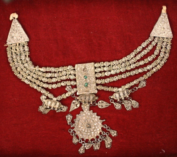 Silberne Halskette mit Smaragden und Diamanten auf rotem Samt.