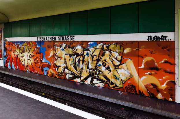 Ein Bahnhof mit einem Bahnsteig auf der linken Seite und einer farbenfrohen, bunt besprühten Wand auf der rechten Seite.