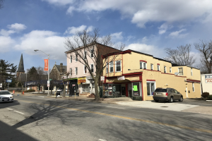 Eine Stadtstraße mit parkenden Autos, Gebäuden, Bäumen, Laternenmasten und Verkehrskegeln, mit Schildern zur Vermietung von Wohnungen an 59 Elmwood Ave, Yonkers 10701.