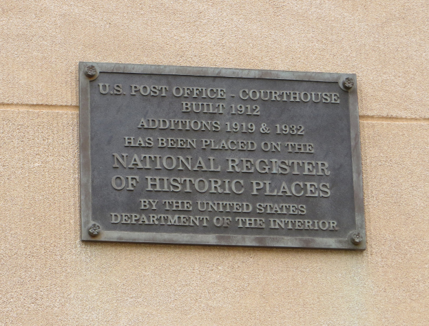 Metallplatte an einer Gebäudewand angebracht, die "National Register of Historic Places" in fetter schwarzer Schrift trägt.