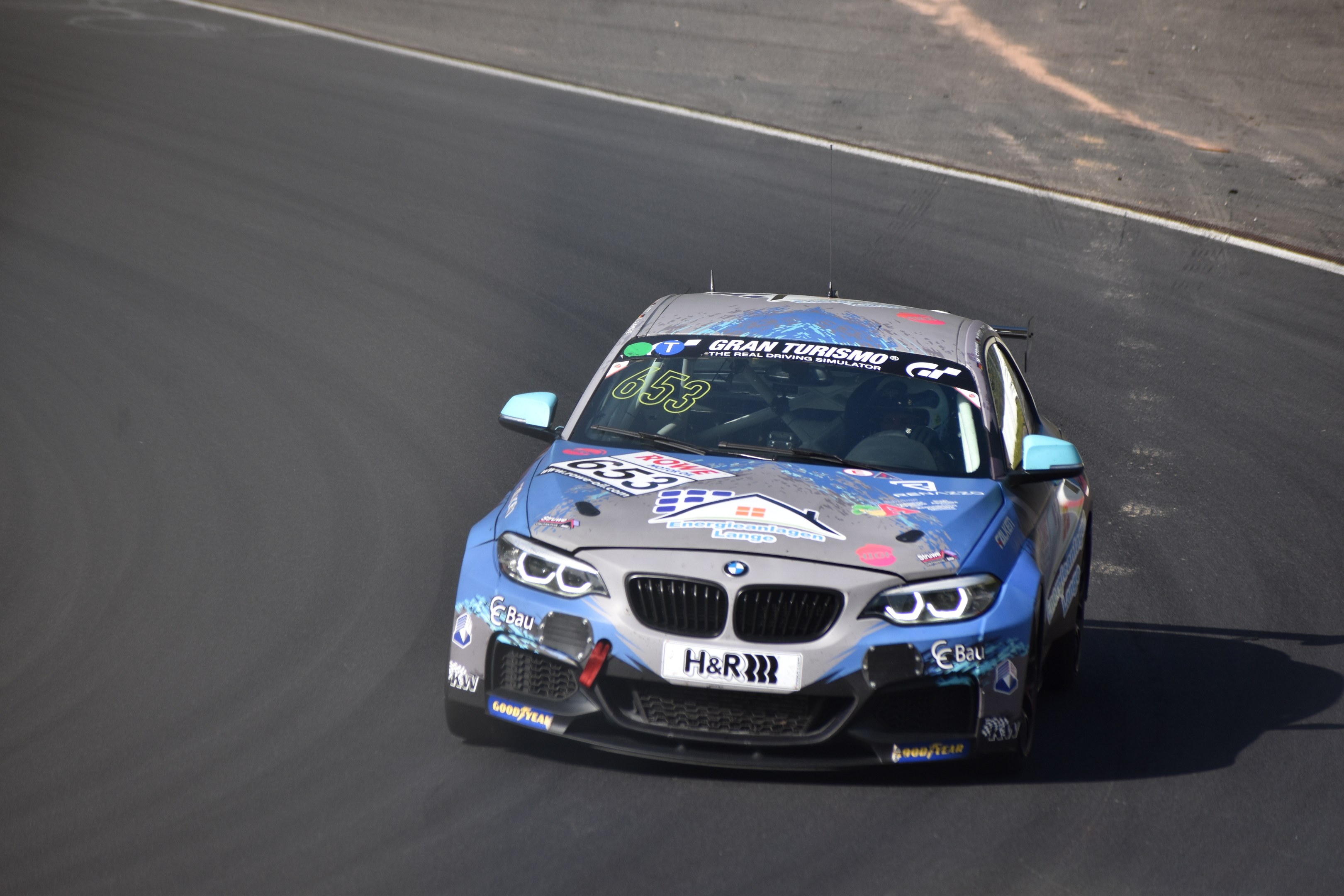 Ein BMW M2 GT3 Rennwagen auf einer Rennstrecke mit Text und Zahlen auf seinem K├Ârper.