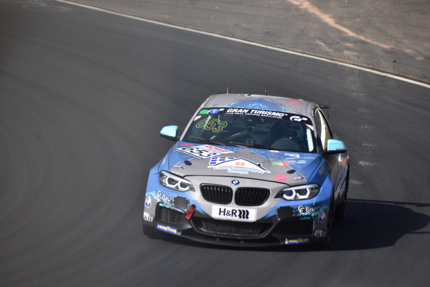 Ein BMW M2 GT3 Rennwagen auf einer Rennstrecke mit Text und Zahlen auf seinem K├Ârper.