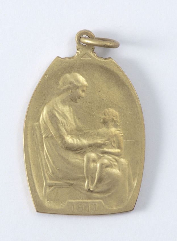 Goldmedaille mit einer Reliefdarstellung einer Frau in einem weißen Kleid mit einem Knoten im Haar, die ein Kind hält, mit der Inschrift "Mutter und Kind" in Kursivschrift.
