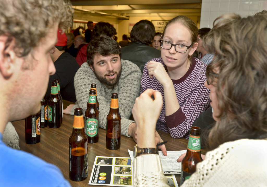 Mehrere Personen an einem Tisch mit Bierflaschen in einer Art Bar.