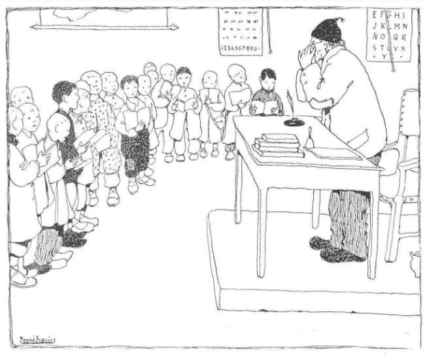 Ein Mann, mutmaßlich ein Lehrer, sitzt an einem Schreibtisch mit Büchern und Gegenständen vor einer Gruppe von Kindern, mit Papieren an der Wand hinter ihm.