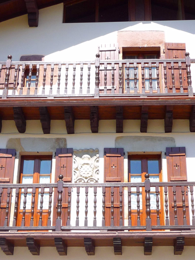 Ein Gebäude mit hölzernen Balkonen mit verzierten Geländern und hölzernen Fenstern.