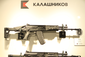 Zwei Sturmgewehre auf einer Waffenmesse mit einer informativen Tafel an der Wand dahinter.