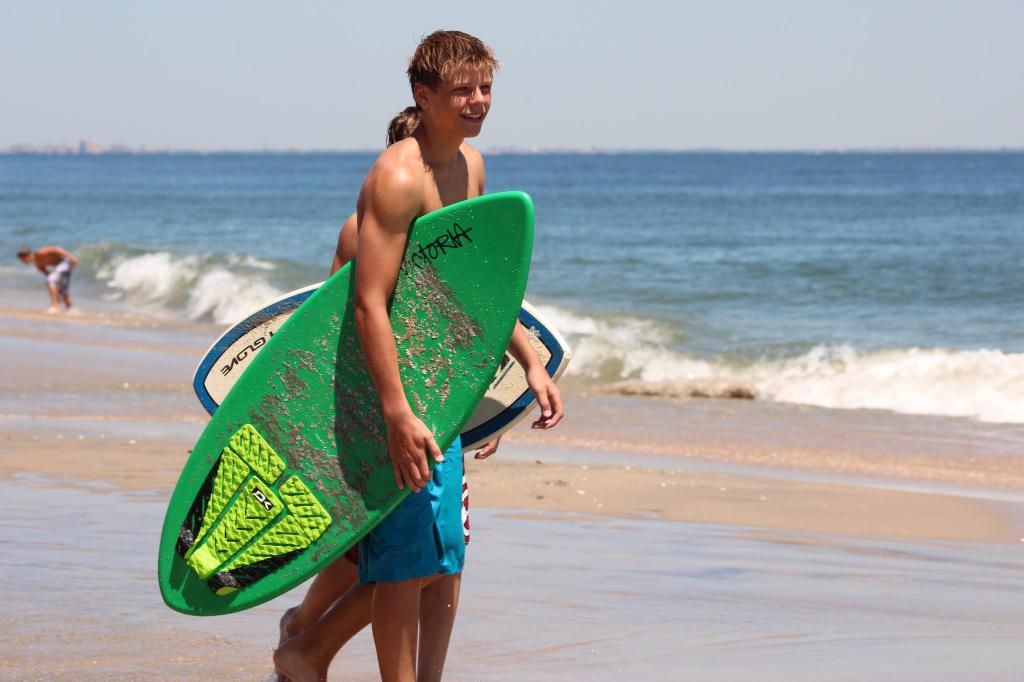 Menschen mit Surfbrettern vor dem Meer.