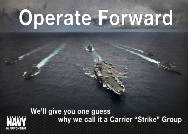 Ein Plakat mit der Aufschrift "Operate Forward - Wir geben Ihnen einen Tipp, warum wir es Carrier Strike Group nennen" mit mehreren Schiffen auf dem Wasser und einem bewölkten Himmel im Hintergrund.