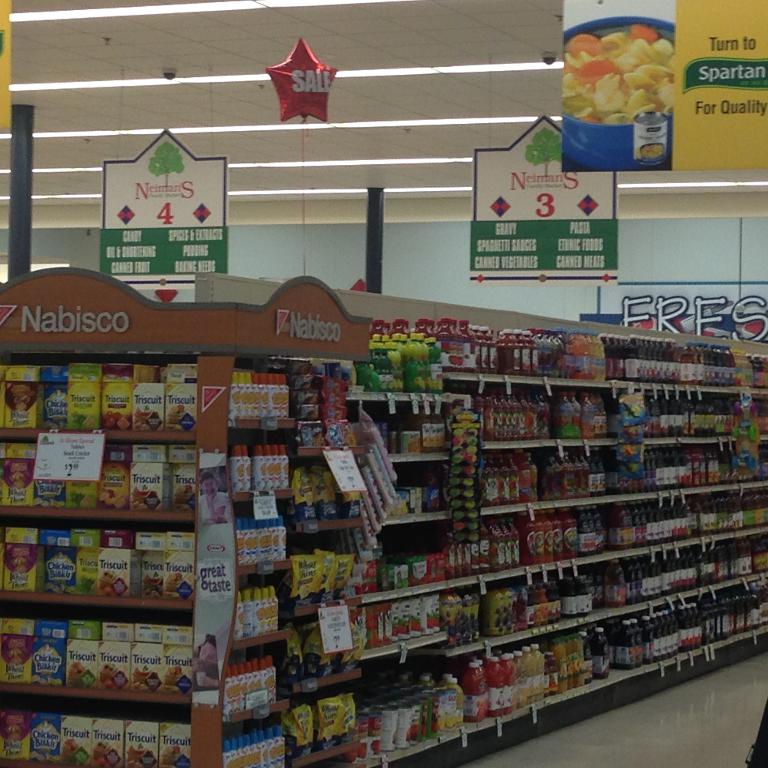 Ein Supermarkt-Innenraum mit sichtbaren Lebensmitteln, Deckenleuchten und Schildern.