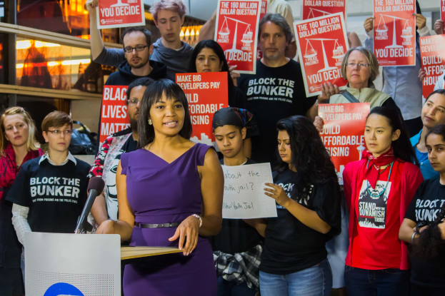 Eine Black Lives Matter-Aktivistin spricht vor einem Publikum mit Mikrofon an einer Tribüne.