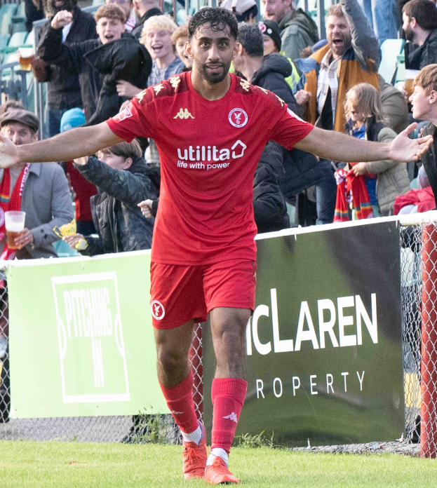 Ein Fußballspieler in roter Uniform rennt mit ausgebreiteten Armen auf einem Feld, umgeben von Zuschauern hinter einer Absperrung, mit einem "Middlesbrough FC v Swansea City - Sky Bet Championship"-Schild im Hintergrund.