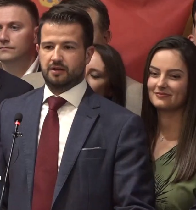 Ein Mann im Anzug spricht vor einem Publikum mit Mikrofon an einem Rednerpult, hinter einem Banner, wahrscheinlich über ein Regierungssozialmedienverbot.