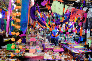 Ein belebter Markt mit Ständen, die Spielzeug, Dekorationsgegenstände und andere Gegenstände verkaufen, unter einer Decke, die mit Lichtern geschmückt ist, mit Menschen, die herumlaufen.