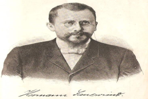 Eine Schwarz-Weiß-Zeichnung eines bärtigen Mannes in einem Blazer und einer Brille, mit dem Text "Hommann Eauwrijk, ein deutscher Komponist und Pianist" unten.