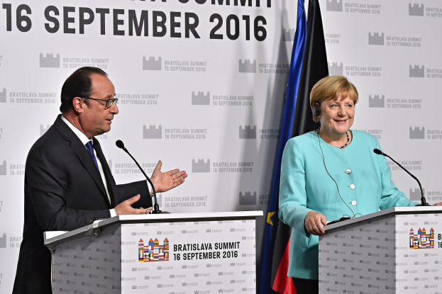 Bundeskanzlerin Angela Merkel und Frankreichs Präsident François Hollande lächeln auf Podien während des Bratislava-Gipfels 2016, mit einem Banner, das den Namen des Ereignisses trägt.