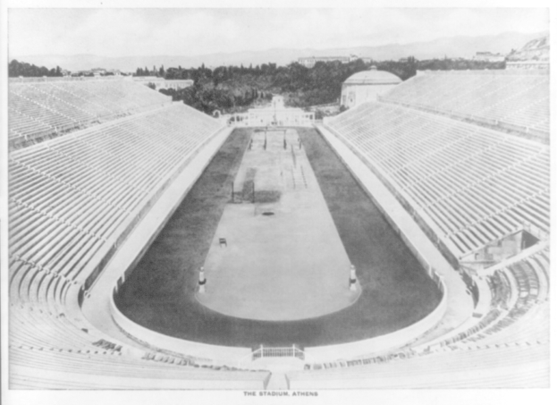 Schwarzes und weißes Foto des Olympischen Stadions in Athen, Griechenland, mit Sitzreihen, umgebenden Bäumen, fernen Gebäuden und Bergen sowie Text am unteren Rand.