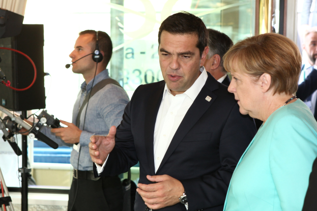 Zwei deutsche Bundeskanzler, Angela Merkel und Joachim Gauck, stehen vor einer Glaswand mit einem Vorhang dahinter, beide in Anzügen und in Mikrofone sprechend.
