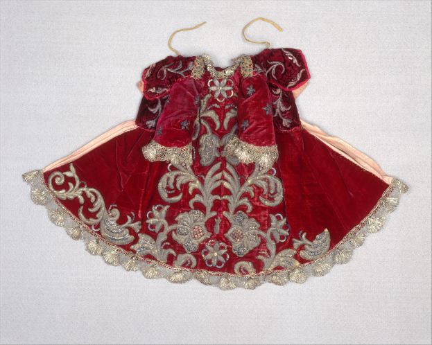 Rotes Samtkleid mit goldener Stickerei und aufwendigen Designs auf einem Bügel gegen einen weißen Hintergrund.