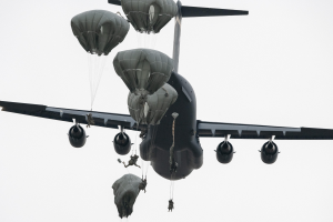 Großes Militärflugzeug mit mehreren Fallschirmen am Himmel