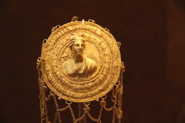 Goldene Medaille mit einer Frauengestalt auf dunklem Hintergrund, mit feinen Details und luxuriösem Aussehen.